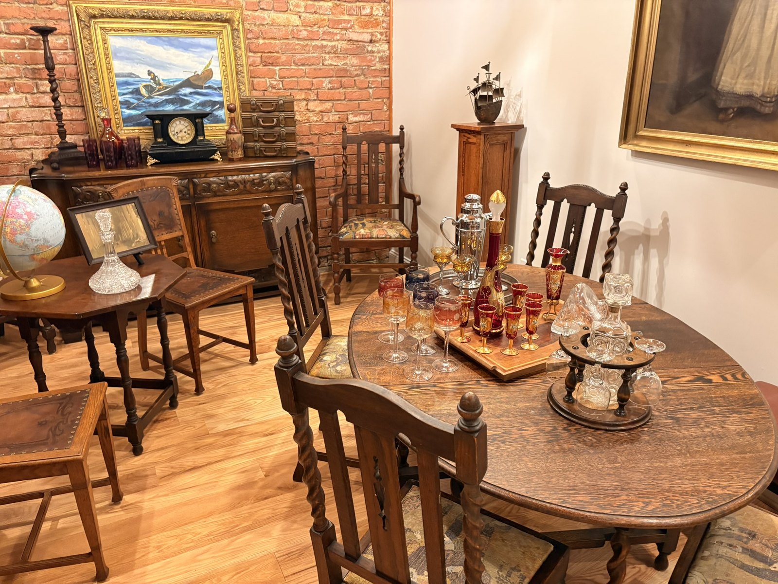 Gilded and ruby cordial glasses and cut-glass decanters arranged on an antique round table in the shop