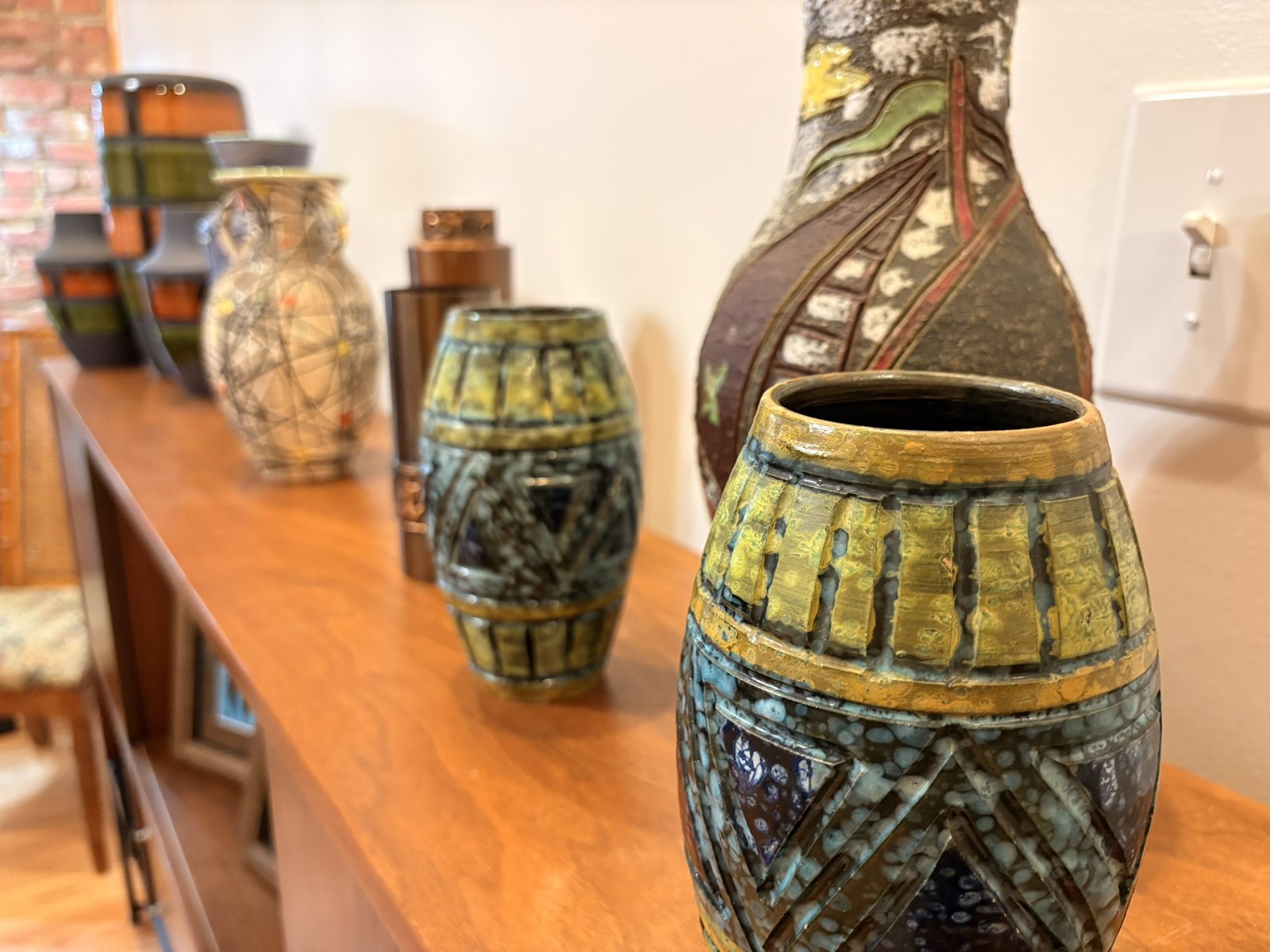 Vintage West German fat lava vases in green and ochre glazes lined up on a walnut credenza
